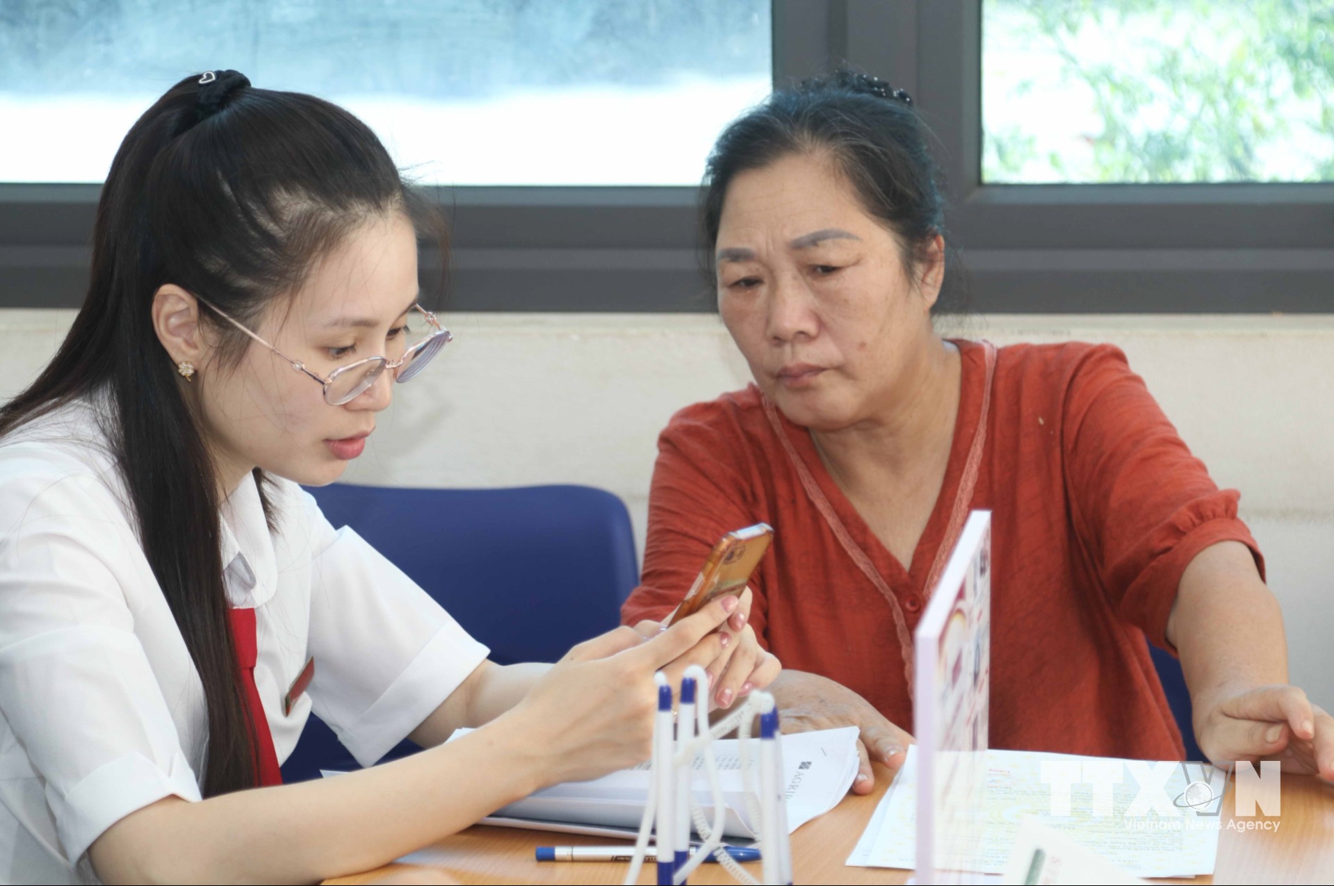 Cán bộ Agribank tỉnh Lạng Sơn hướng dẫn người dân thực hiện thủ tục hành chính trên các nền tảng số. (Ảnh: Quang Duy/TTXVN)